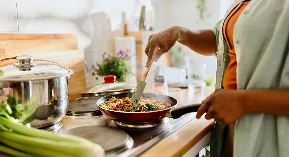 personne préparant un repas sur une cuisinière dans la cuisine